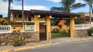 a yellow house with a stone wall next to a street at Pousada da Rose Paraty in Paraty