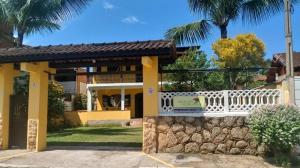 une maison avec une clôture blanche et des palmiers dans l'établissement Pousada da Rose Paraty, à Parati