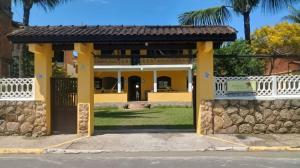 une porte menant à une maison jaune avec un mur en pierre dans l'établissement Pousada da Rose Paraty, à Parati