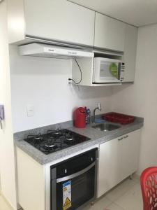eine Küche mit Herd, Spüle und Mikrowelle in der Unterkunft Flat Centro de Porto de Galinhas Laguna Beach Flat in Porto De Galinhas