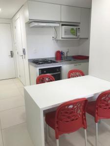 eine Küche mit einer weißen Theke und roten Stühlen in der Unterkunft Flat Centro de Porto de Galinhas Laguna Beach Flat in Porto De Galinhas