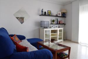 a living room with a blue couch and a coffee table at Apartamento frente a Palacio de Congresos (Fibes) in Seville