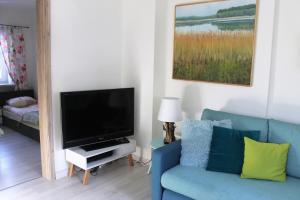 a living room with a blue couch and a television at Andrzejówka in Borowe