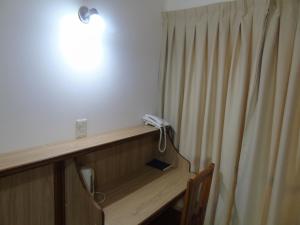 a room with a desk with a phone next to a curtain at Urunday Apart Hotel in Posadas