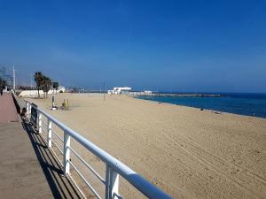 een zandstrand met een wit hek en de oceaan bij Rambla Poblenou&Mar Bella Beach in Barcelona