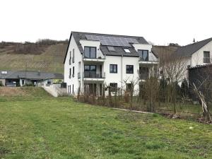 una grande casa bianca con pannelli solari di FEWO Klosterblick a Zeltingen-Rachtig
