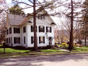 a white house with a fence in front of it at 18 Vine Inn & Carriage House in Hammondsport