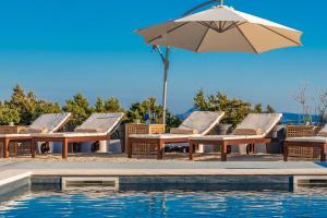 a group of chairs and an umbrella next to a pool at Villa Olea, luxury retreat with nature blend in Novalja