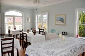a dining room with white tables and chairs and windows at The Sunset Inn in Sunset Beach