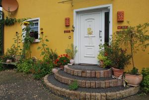 una casa amarilla con una puerta blanca y algunas plantas en Casa Ramke, en Eitorf