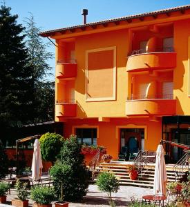 un edificio naranja con sillas y balcón en Hotel Ristorante Montenerone en Apecchio