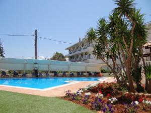 a hotel with a swimming pool in front of a building at Perla Beach in Agia Marina Nea Kydonias