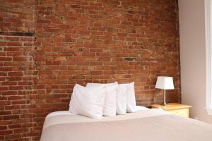 una pared de ladrillo detrás de una cama con almohadas blancas en Stylish Downtown Studio in the South End, #8, en Boston