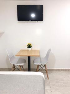 a table with two chairs and a television on a wall at KLEINN HOTEL BOGOTÁ in Bogotá