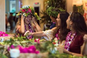 Un groupe de femmes assises à une table avec des fleurs sur la tête dans l'établissement Queen Kapiolani Hotel, à Honolulu