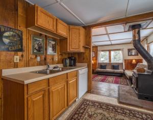 une cuisine avec des placards en bois et un évier, ainsi qu'un salon dans l'établissement Zuni's Cabin, à Leadville