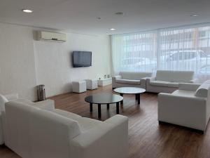 a living room with white furniture and a flat screen tv at Flat lindo a 120 metros da praia de Riviera de São Lourenço até 4 pessoas in Bertioga