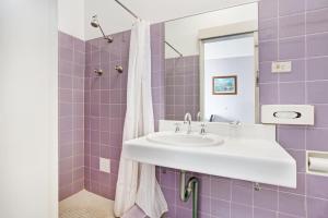 een paarse badkamer met een wastafel en een spiegel bij Gateshead Tavern & Motel in Charlestown