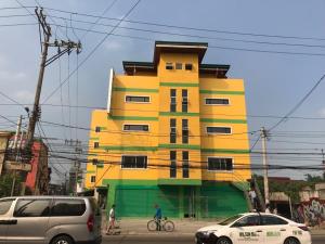 een geel en groen gebouw met auto's geparkeerd voor het bij Meaco Royal Hotel - Malabon in Manilla