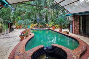 uma piscina num jardim com um pátio de tijolos em Ancient Gardens Guesthouse & Botanical Gardens em Eudlo