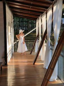 a woman in a white dress walking down a porch at Hotel Ballena Dorada in Uvita