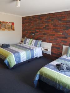 a bedroom with two beds and a brick wall at Coorrabin Motor Inn in Stawell +33 photos