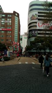 新竹市的住宿－柿子紅快捷旅店，一群人沿着街道走着,街道上有许多建筑