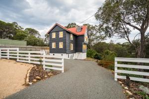 a black house with a white fence next to it at The Oar House in Metung