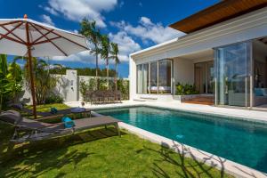 a villa with a swimming pool and a house at Trichada Villas in Bang Tao Beach