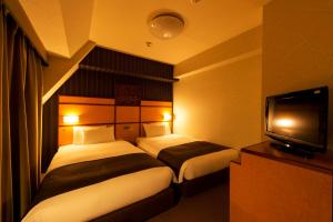 a hotel room with two beds and a flat screen tv at Hotel Villa Fontaine Tokyo-Hamamatsucho in Tokyo