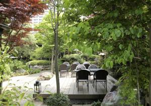 une table et des chaises assises sur une terrasse dans un jardin dans l'établissement CASA KUNISAKU, à Machida