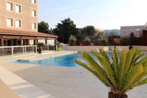 a swimming pool with a palm tree next to a building at Best Western Marseille Aeroport in Vitrolles