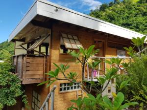 une maison en bois avec un balcon et des arbres dans l'établissement Fare Matatia, à Punaauia