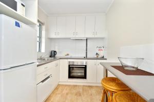 a white kitchen with white cabinets and a counter at Dolphin Lodge Albany - Self Contained Apartments at Middleton Beach in Albany