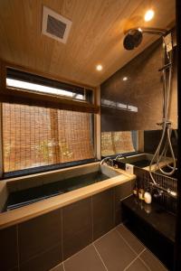 a bathroom with a bath tub and a window at Tsumugi Kiyomizugojo in Kyoto