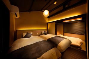 a bedroom with two beds and a window in it at Tsumugi Kiyomizugojo in Kyoto