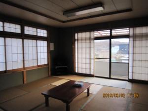 an empty room with a table and windows at Minshuku Kobayashi in Narusawa