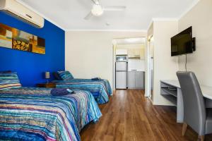 a room with two beds and a desk and a television at The Cove Holiday Village in Point Samson