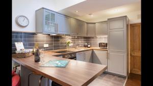 a kitchen with a wooden table and a clock on the wall at Secret City Cottage - Peaceful - Private Garden in Aberdeen
