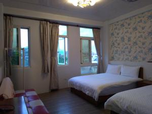 a hotel room with two beds and two windows at Grapefruit Heping Guesthouse in Hualien City