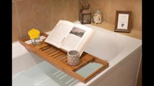 a book on a wooden tray on a bath tub at Secret City Cottage - Peaceful - Private Garden in Aberdeen +28 photos