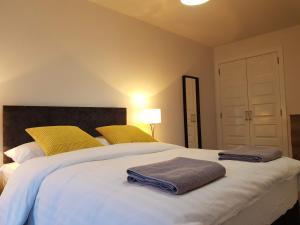 um quarto com uma grande cama branca com almofadas amarelas em 11 Royal View Apartments em Stirling