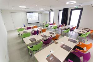 una classe con tavoli, sedie e schermo di proiezione di Nex Hôtel a Tarbes