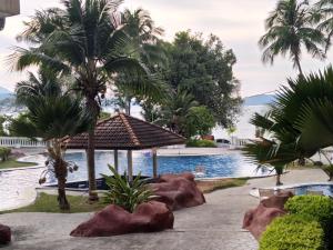 a swimming pool with palm trees and a resort at The Orient Star Resort Lumut in Lumut