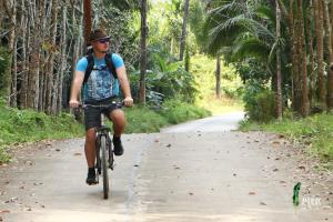 een man die fietst over een weg bij Anurak Community Lodge - SHA Plus in Khao Sok