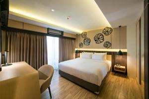 a hotel room with a bed and a chair in it at Nadee 10 Resort & Hotel in Khon Kaen
