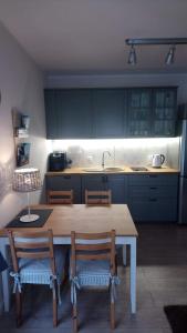 cocina con mesa de madera con sillas y fregadero en Apartament 13 Ustronie Morskie en Ustronie Morskie