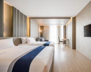 a hotel room with two beds and a television at Zayn Hotel Bangkok - SHA Plus Certified in Bangkok