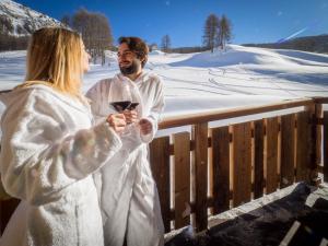 a man and woman in white robes holding a glass of wine at Residence Livigno MyHolidayLivigno in Livigno