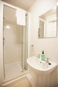 a white bathroom with a sink and a shower at Glascoed Guest House in Llandudno